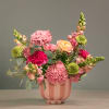 Pink and peach mixed flower arrangement in a striped pink vase