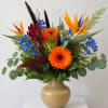 Bright mixed bouquet in a beige vase with orange and blue flowers