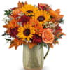 Autumn bouquet of sunflowers, roses, and mums in a ceramic pitcher