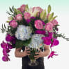 Tall arrangement of pink roses, white lilies, blue hydrangeas, and fuchsia orchids in a clear glass vase