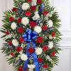 Standing floral spray with red, white, and blue flowers and a blue ribbon bow