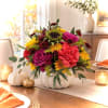 Colorful floral arrangement in a white pumpkin-shaped vase on a dining table