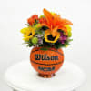 Flower arrangement in a basketball-shaped container with orange lilies and sunflowers