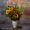 Sunflower arrangement in a white vase with yellow and orange accents