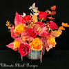 A bold arrangement of red roses, orange ranunculus, and tropical accents, capturing