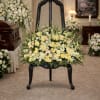 Large white and pale yellow floral spray on a black chair in a chapel