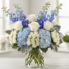 Blue and white floral arrangement in a clear glass vase