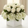 White roses and hydrangeas arranged in a white square vase