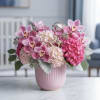 Pink orchid and hydrangea arrangement in a blush vase with a small rocking horse