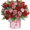 Red and pink flower arrangement in a patterned glass vase