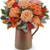 Bouquet of peach and orange roses in a brown pitcher vase