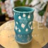 Turquoise ceramic vase with white teardrop and floral patterns