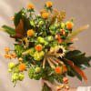 Handheld bouquet with orange blooms and green flowers in a loose, airy design