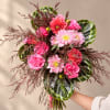 Handheld bouquet of pink flowers with dark patterned leaves