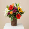 Mixed bouquet of roses, lilies, sunflowers, and mums in a wooden vase