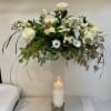 White floral arrangement in a tall clear vase with a candle inside