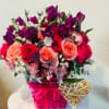 Bouquet of pink, red, and purple flowers in a pink basket with a woven heart