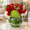 Red roses and white flowers arranged in a round glass vase