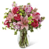 Pink roses and lilies arranged in a clear glass vase
