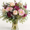 Mixed bouquet of pink and peach flowers in a clear glass vase