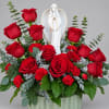 Red roses and carnations arranged around a white angel figurine in a vase