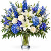 Blue and white bouquet with lilies, roses, and irises in a clear glass vase