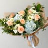 Hand-tied bouquet of peach roses, blue hydrangeas, and white blooms