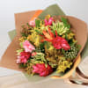 Bouquet of bright tropical flowers wrapped in brown and green paper