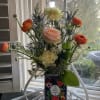 Mixed bouquet of roses, ranunculus, and blue thistle in a decorative box