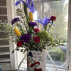 Mixed bouquet in a decorative vase with blue irises and yellow tulips