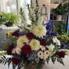 Large mixed flower arrangement in a wicker basket with red roses and white blooms