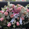 Large pink rose and lily arrangement with white filler flowers and a silver ribbon