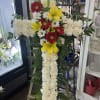Standing floral cross with white carnations, red gerberas, and yellow lilies