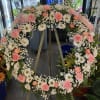 Large pink and white floral wreath on a stand with a ribbon