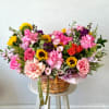 Mixed bouquet in a wicker basket with pink roses and sunflowers