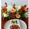 Peach and white floral arrangement with autumn leaves on a table setting