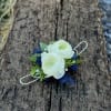 White ranunculus boutonniere with blue ribbon on weathered wood