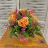 Orange roses in a pink glass vase with magenta filler flowers