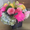 Mixed bouquet of pink roses, yellow roses, hydrangea, and bright pink mums in a black vase