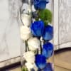 Tall glass vase with white and blue roses and small accent flowers