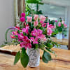 Pink flowers arranged in a white vase with a line drawing on it