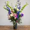 Tall mixed bouquet in a black vase with pink lilies and blue flowers