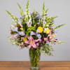 Mixed bouquet of lilies, roses, and snapdragons in a clear glass vase