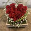 Red roses arranged in a square wooden box with white baby's breath