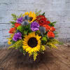 Colorful bouquet with sunflowers, roses, and purple blooms in a rustic wood container