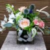 Mixed bouquet with pink roses and white flowers in a square glass vase