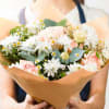 Bouquet of pink roses and white daisies wrapped in tan paper