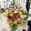 Bouquet of pink and yellow roses with mixed flowers wrapped in beige paper