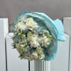 Bouquet of white roses and pale blooms wrapped in light blue paper