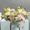 Basket arrangement of pale pink and white roses with yellow blooms and ribbon